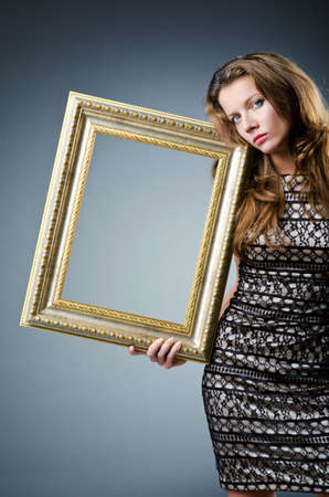 Young woman with picture frame on whiteの写真素材