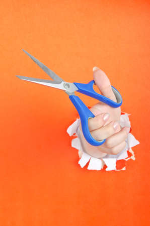 Hand with scissors from paper holeの写真素材
