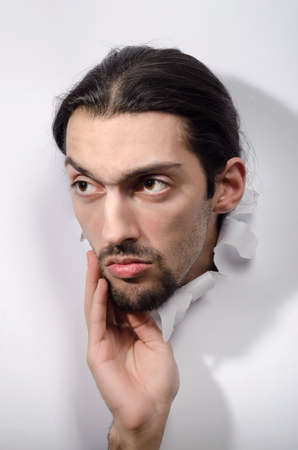 Male face through the hole in paperの写真素材