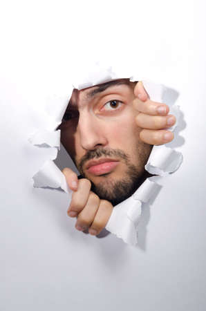 Male face through the hole in paperの写真素材