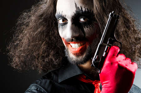 Evil clown with gun in dark room