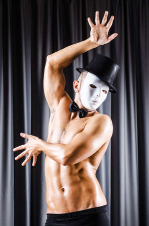 Muscular actor with mask against curtainの写真素材