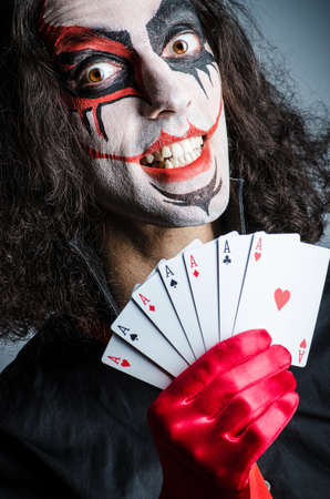 Evil clown with cards in dark room