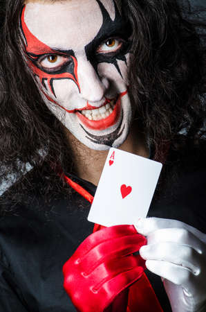 Evil clown with cards in dark roomの写真素材