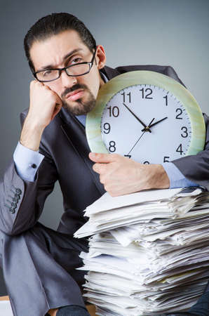 Man with clock and pile of papersの写真素材