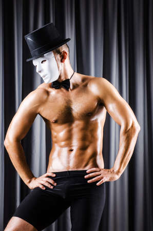 Muscular actor with mask against curtainの写真素材