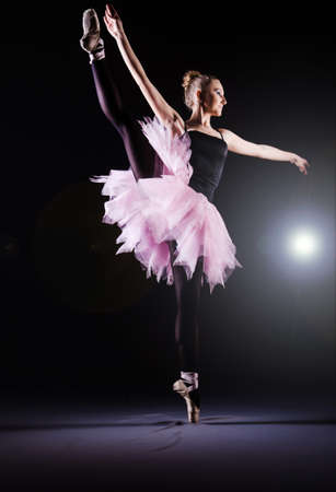 Ballerina dancing in the dark studio
