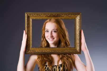 Redhead with picture frame against dark backgroundの写真素材