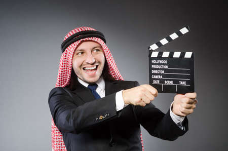 Arab man with movie clapper against grey backgroundの写真素材