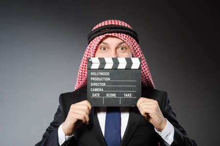 Arab man with movie clapper against grey backgroundの写真素材
