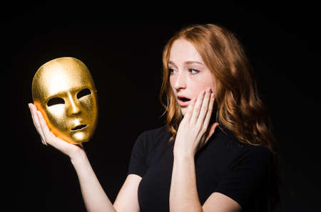 Redhead woman iwith mask in hypocrisy consept against black  backgroundの写真素材