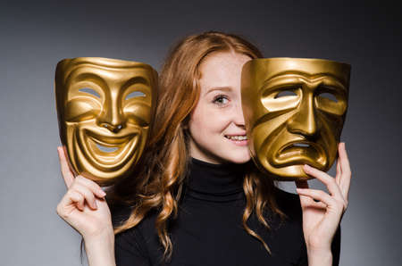Redhead woman iwith masks in hypocrisy consept against grey background