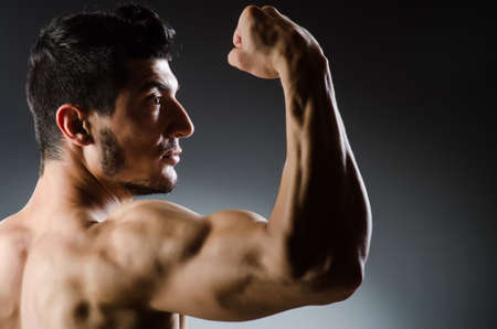 Muscular man posing in dark studio