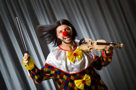 Funny clown plyaing violin against curtainの写真素材