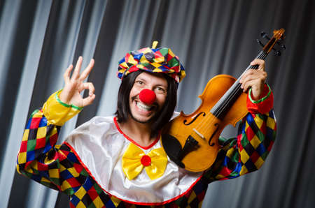 Funny clown plyaing violin against curtainの写真素材