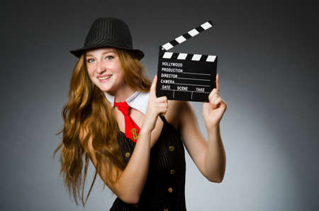 Woman with movie clapboard against grey backgroundの写真素材