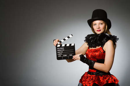 Woman with movie clapboard against grey background