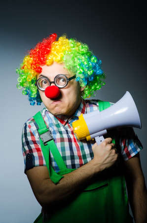Clown with loudspealer against curtainの写真素材