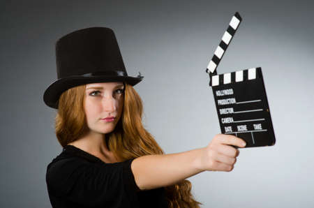 Woman with movie clapboard against grey backgroundの写真素材