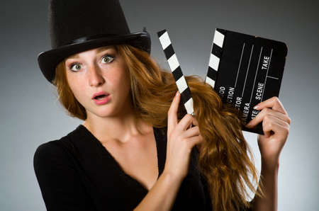 Woman with movie clapboard against grey background
