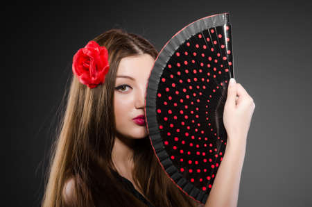 Beautiful young woman with flower and fanの写真素材