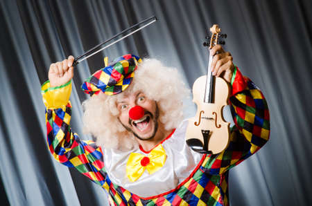 Funny clown plyaing violin against curtainの写真素材