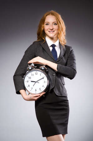 Businesswoman with clock being late for her deliverablesの写真素材