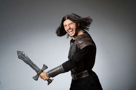 Angry knight with sword against dark backgroundの写真素材