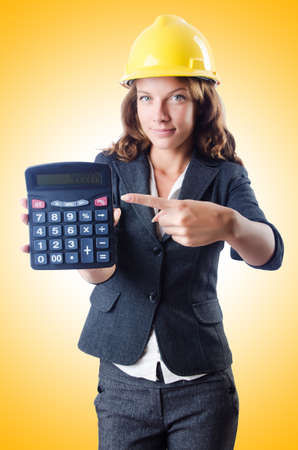 Female builder with calculator on whiteの写真素材