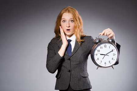 Businesswoman with clock being late for her deliverablesの写真素材