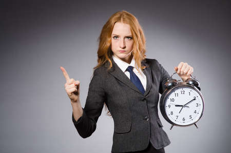 Young nice businesswoman with alarm clock pointingの写真素材