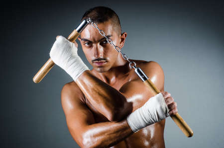Man with nunchucks against dark backgroundの写真素材