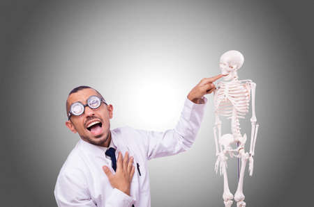 Funny doctor with skeleton isolated on whiteの写真素材