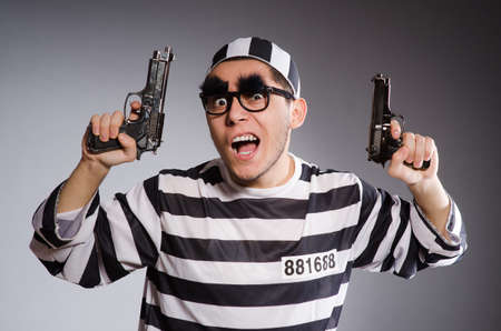 Funny prisoner with weapon isolated on gray