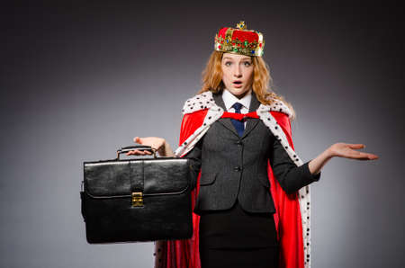 Pretty businessman with crown and case isolated on grayの写真素材