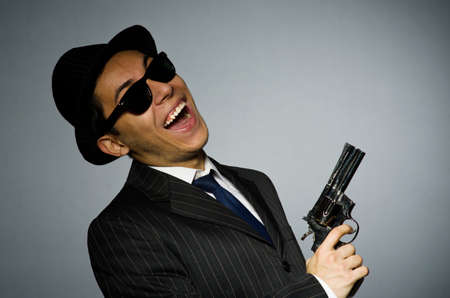 Young man in classic striped costume holding gun isolated on grayの写真素材