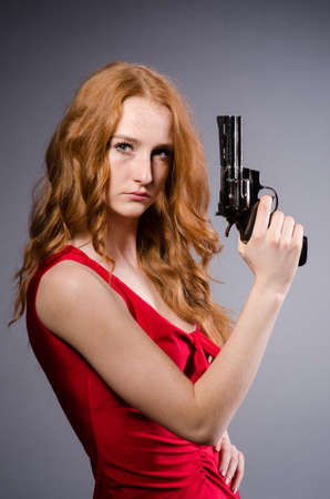 Pretty young girl in red dress with gun isolated on whiteの写真素材
