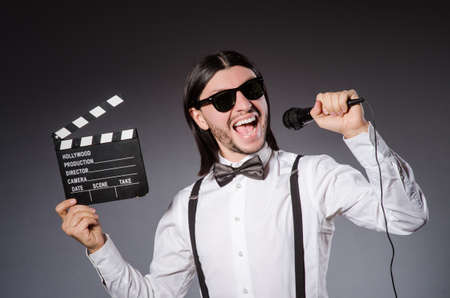 Positive man holding clapperboard and microphone isolated on grayの写真素材