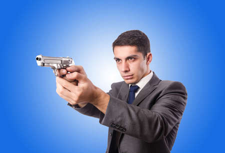 Businessman with gun against the gradientの写真素材