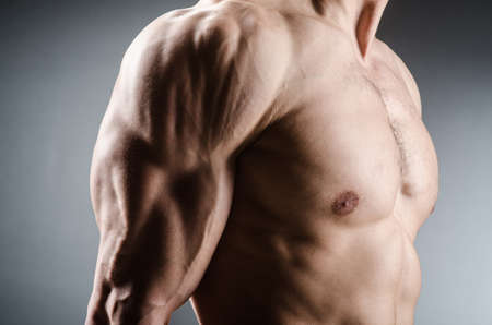Muscular man posing in dark studio