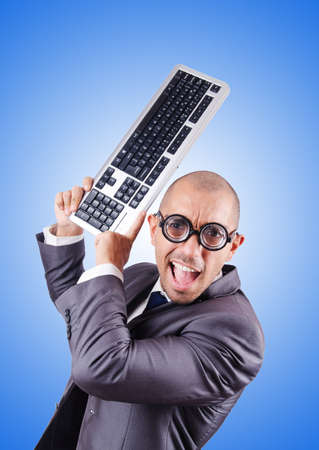 Nerd businessman with computer keyboard against gradientの写真素材