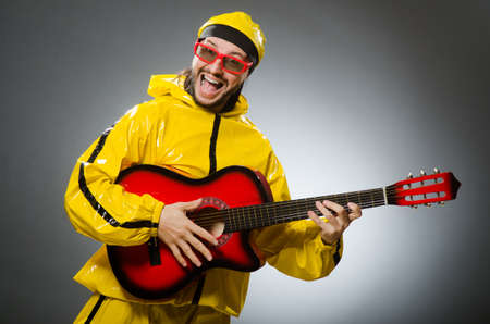 Funny man wearing yellow suit and playing guitar