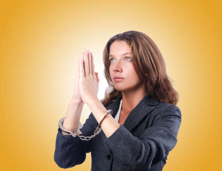 Female businesswoman with handcuffs against gradientの写真素材