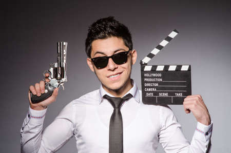 Young man in cool sunglasses holding gun isolated on grayの写真素材
