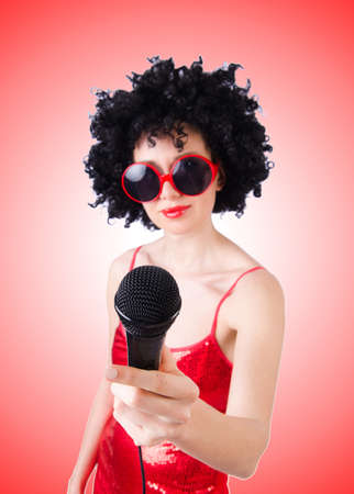 Pop star with mic in red dress against gradientの写真素材
