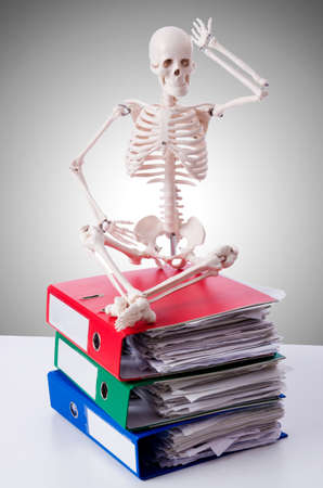 Skeleton with pile of files against gradientの写真素材