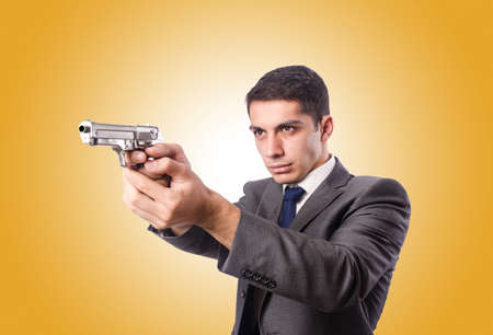Businessman with gun against the gradientの写真素材