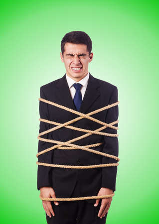 Businessman tied up with rope against gradientの写真素材