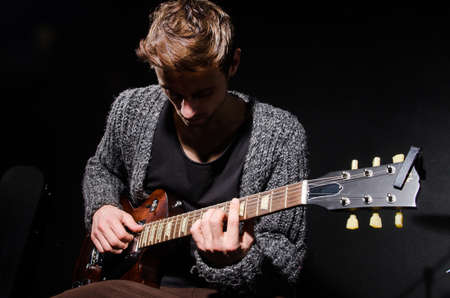 Man playing guitar in dark roomの写真素材