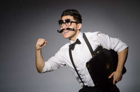 Young man with false moustache holding case  isolated on grayの写真素材